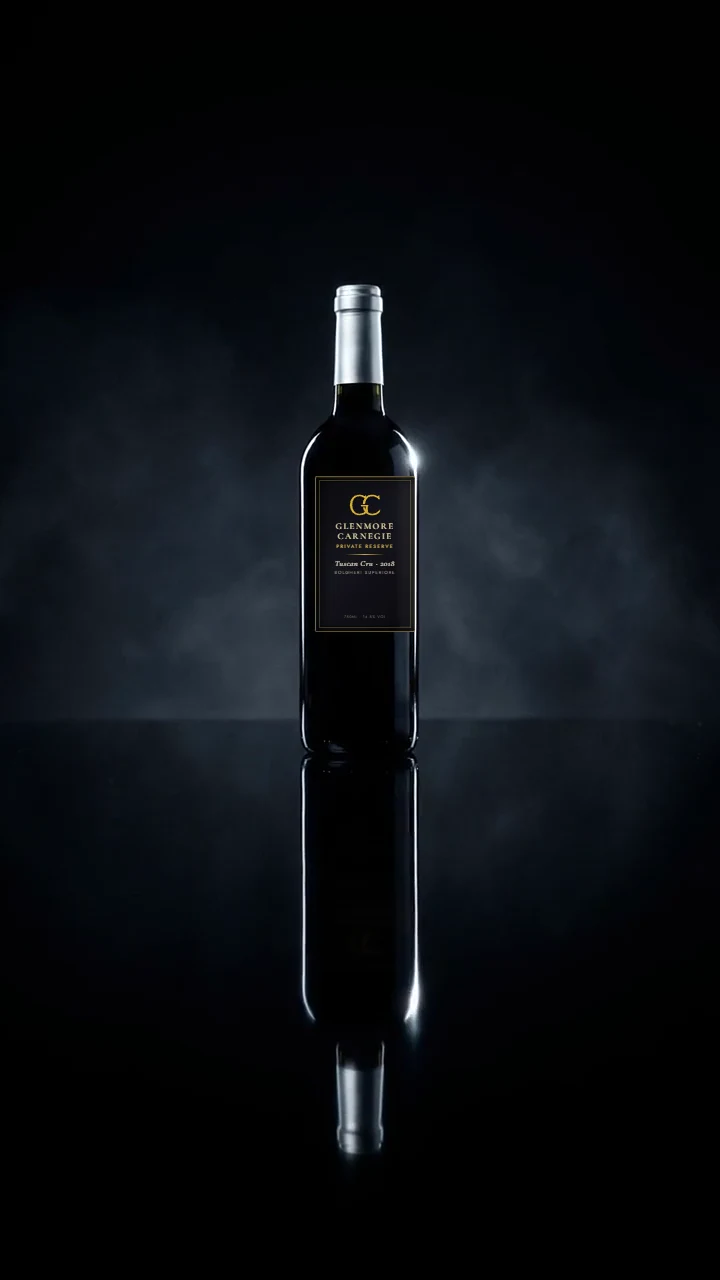 An unlabelled dark wine bottle with a silver capsule standing in drifting smoke